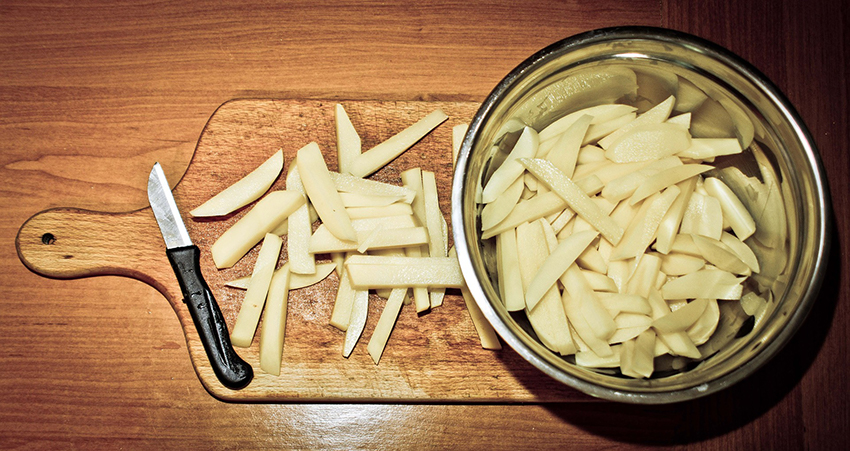 Kartoffeln sind geschält und in Streifen geschnitten, um Pommes daraus zu machen