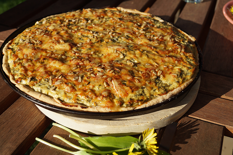 Goldbraun leuchtet die Quiche auf dem Holzbrett