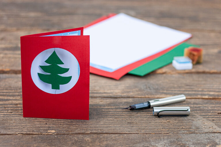 Die aufgestellte Karte liegt vor gleichfarbigen Materialien in grün, weiß, blau und rot, sowie einem Füller.