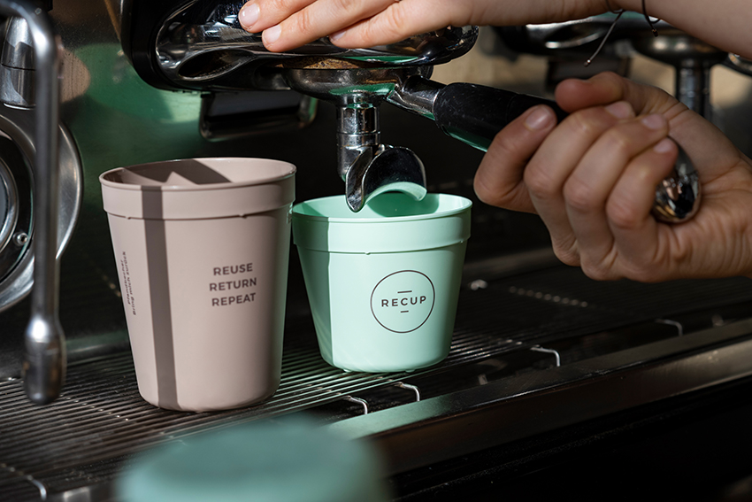 In einen kleinen Kaffeebecher von RECUP wird Kaffee aus einer Siebträgermaschine gefüllt.