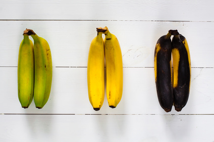 Twee groene, twee gele en twee bruine bananen liggen naast elkaar.