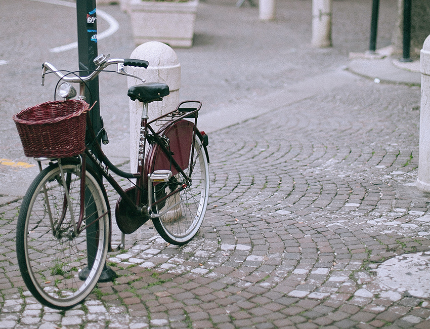 Ein Fahrrad mit einem geflochtenem Korb steht an einer Laterne. Korb