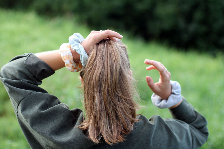 Frau macht sich mit den selbst genähten Scrunchies einen Zopf.