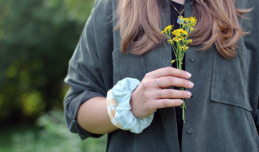 Frau trägt zwei selbst genähte Scrunchies als Armbänder am Handgelenk und hält Blumen in der Hand.
