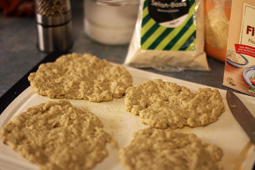 Die Seitanschnitzel liegen bereit zum Panieren auf einem Brettchen.