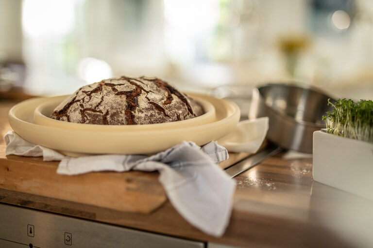 Ein gebackenes Brot steht in einer Backform zum Auskühlen auf der Küchentheke.