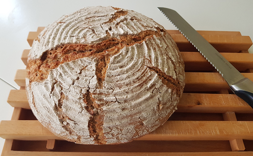 Ein selbst gebackenes Brot lieg auf einem Schneidebrett.