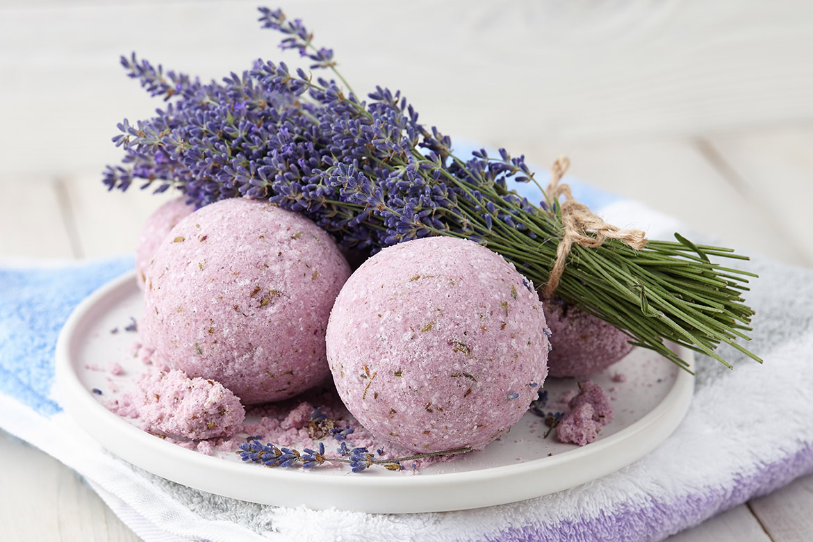 Paarse badbommen op een wit bord met lavendeltakjes