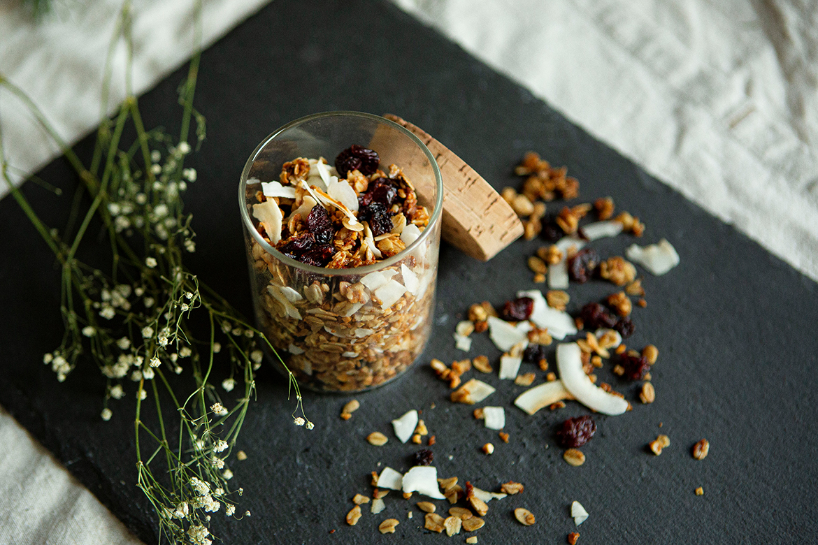 Selbst gemachtes Granola steht in einem kleinen Gefäß auf einer Schieferplatte.