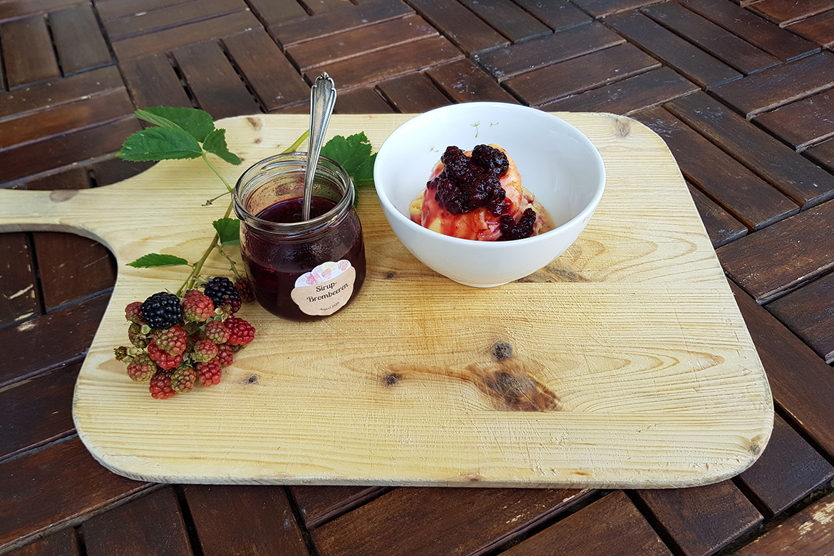 Ein Glas Sirup-Brombeeren und eine Schüssel Vanilleeis.