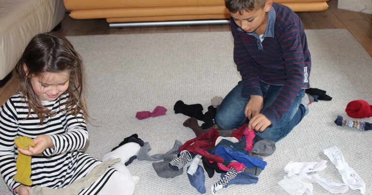 Zwei Kinder spielen auf dem Boden mit Socken.