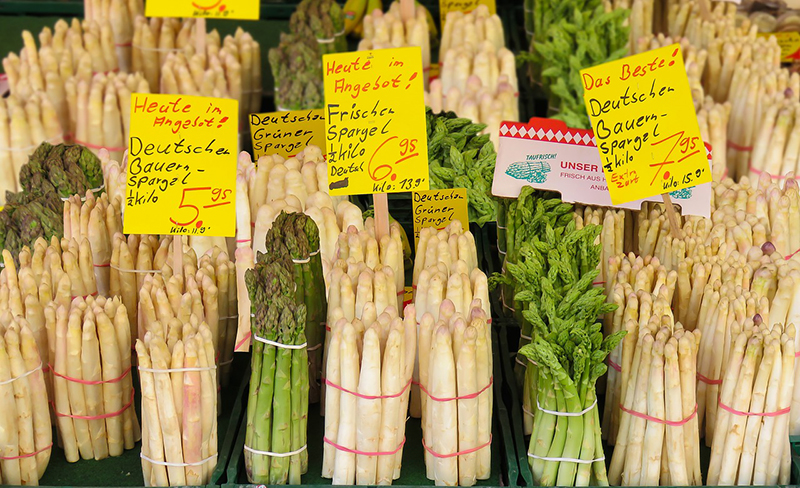 Gebündelt stehen viele weiße, aber auch grüne und Wildspargelstangen auf de Marktstand.