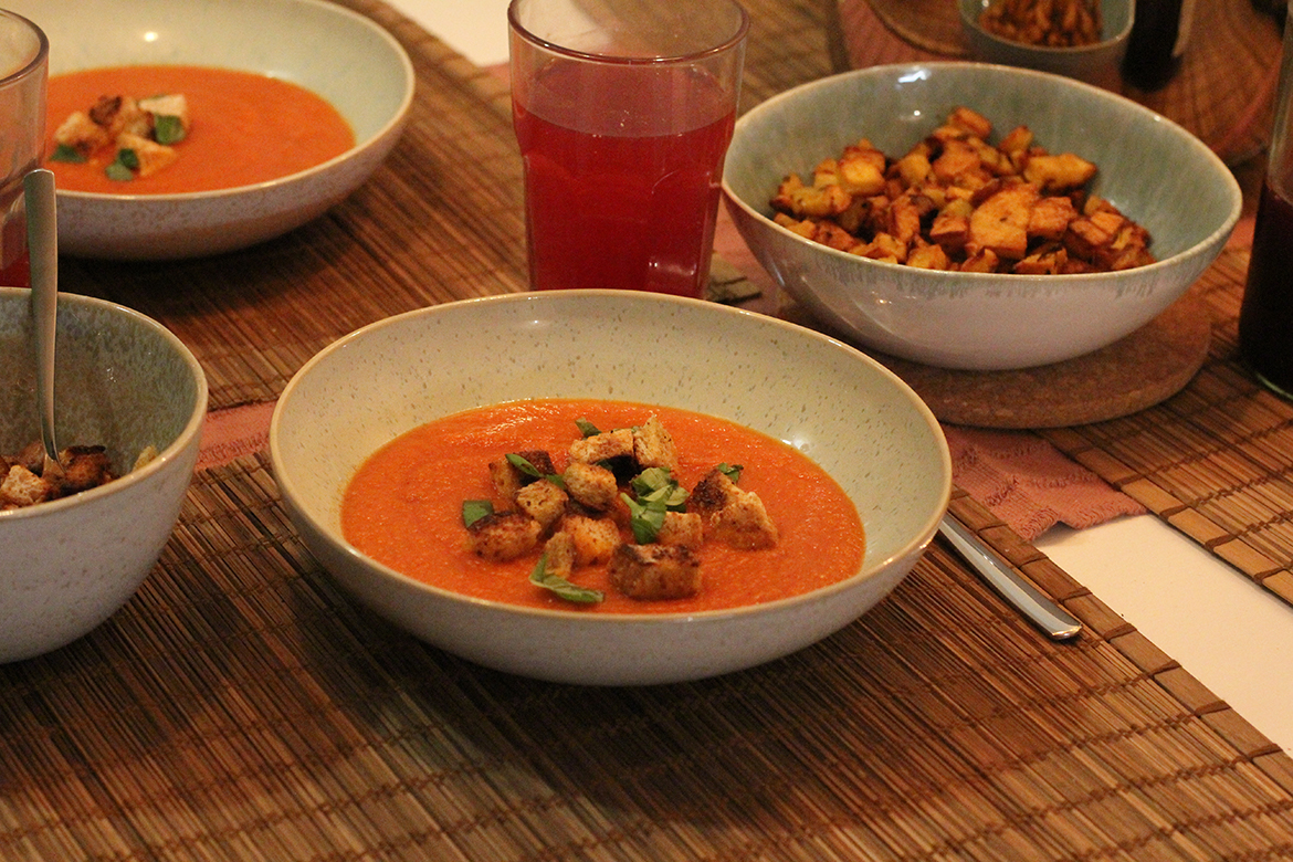 Tomatensuppe ist in Schüsseln serviert und mit Basilikum und Croutons verfeinert.