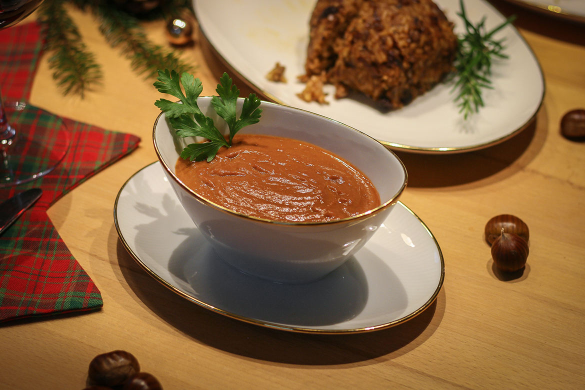 In einer weißen Sauciere steht die Bratensauce auf dem Tisch.