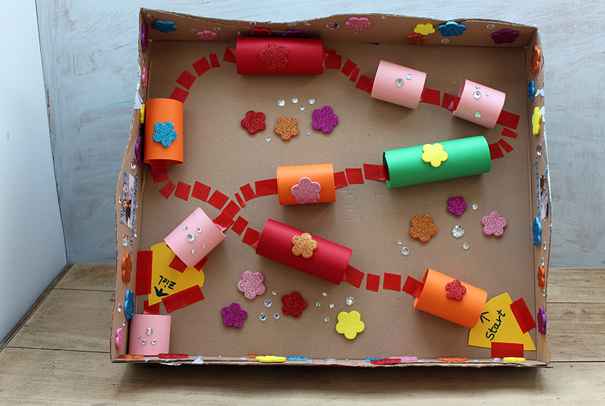 Das Geschicklichkeitsspiel aus Karton lehnt an einer Wand und wurde mit bunten Blumen und Farben verziert.
