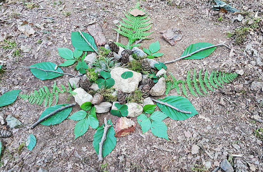 Ein Waldmandala wurde aus Blättern, Steinen und Stöcken auf dem Waldboden gelegt.