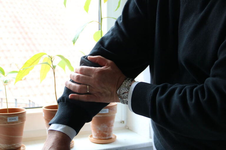 Ein Mann streicht mit der Hand über seinen Pullover.