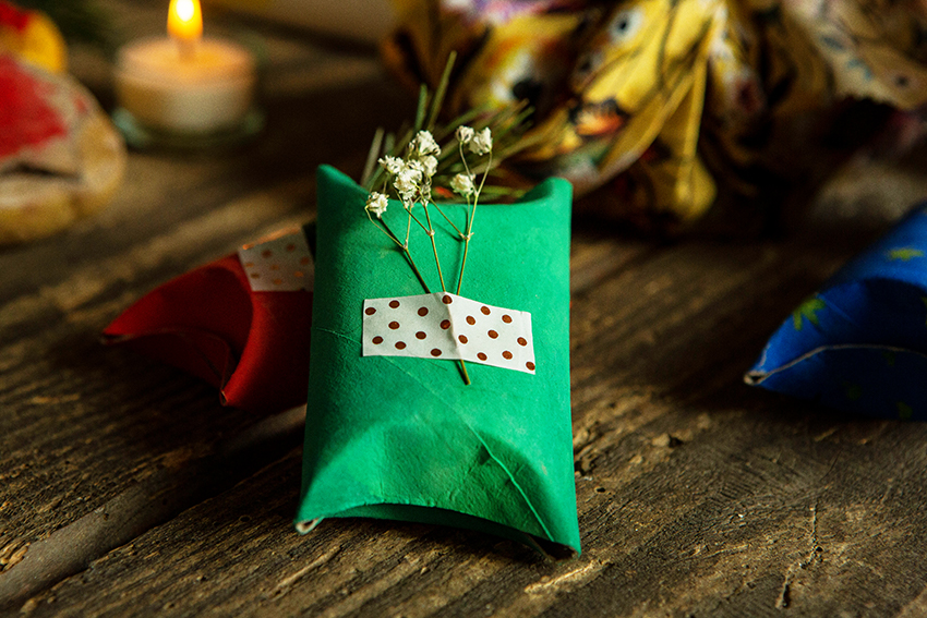 Eine Klopapierrolle ist verziert und grün bemalt und dient als nachhaltige Geschenkverpackung.