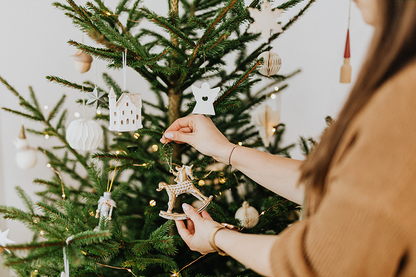 Ein Tannenbaum wird mit Baumschmuck dekoriert.