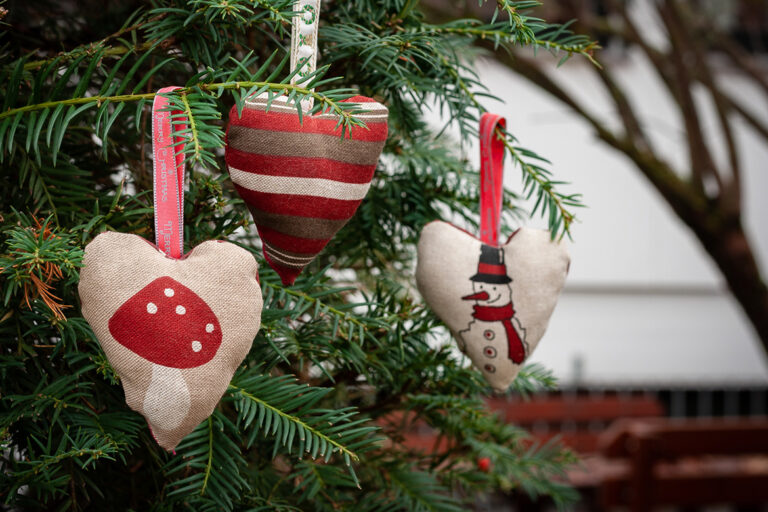 Drei selbst genähte Weihnachtsbaumanhänger aus Stoff an Tannenzweigen