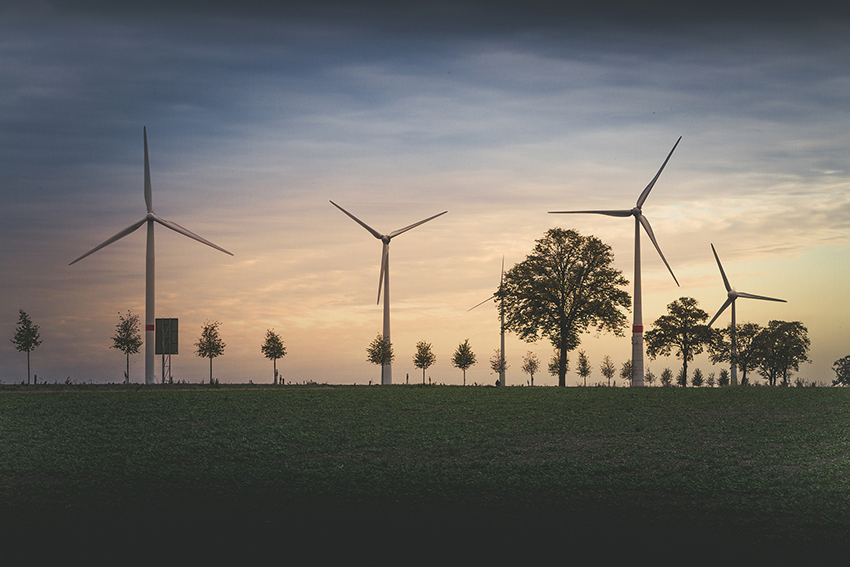 Ökobanken investieren in erneuerbare Energien wie den Ausbau von den auf der Wiese stehenden Windrädern.