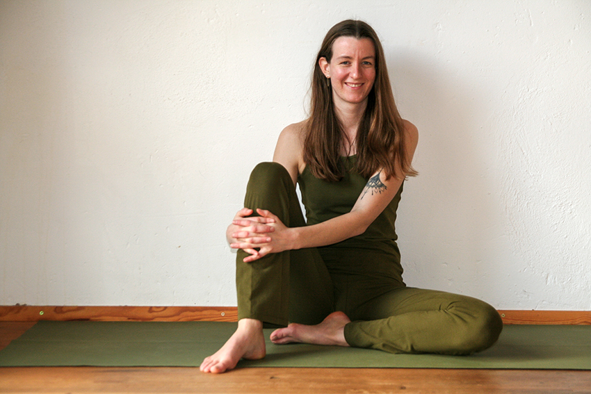 Yogalerares Lea Uhle zit op een yogamat.