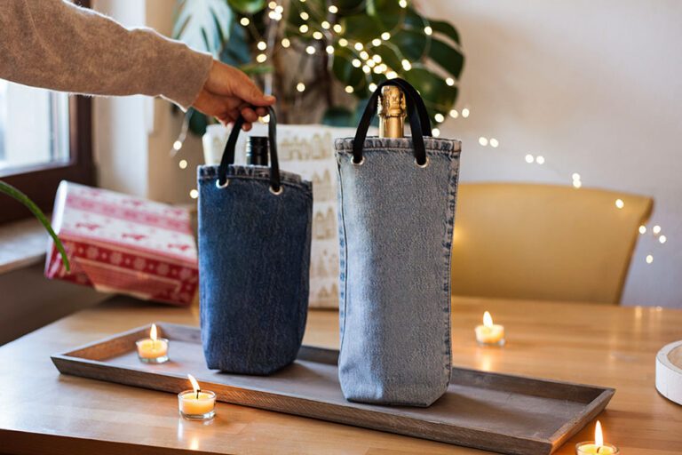 Zwei selbst genähte Flaschentaschen aus Jeans stehen aus einem Tisch.