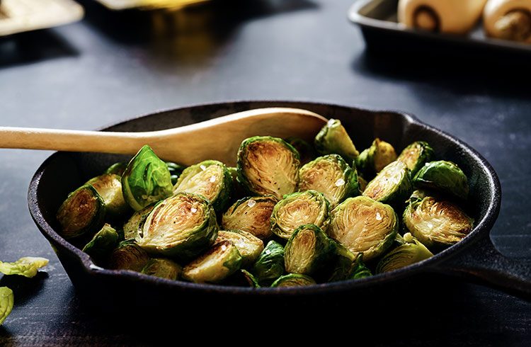 Spruitjes worden in een ijzeren pan met een houten spatel omgedraaid.