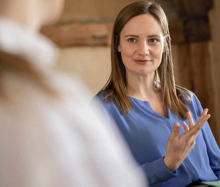 Eine Frau unterstreicht mit ruhigen Handbewegungen ihre Aussagen.