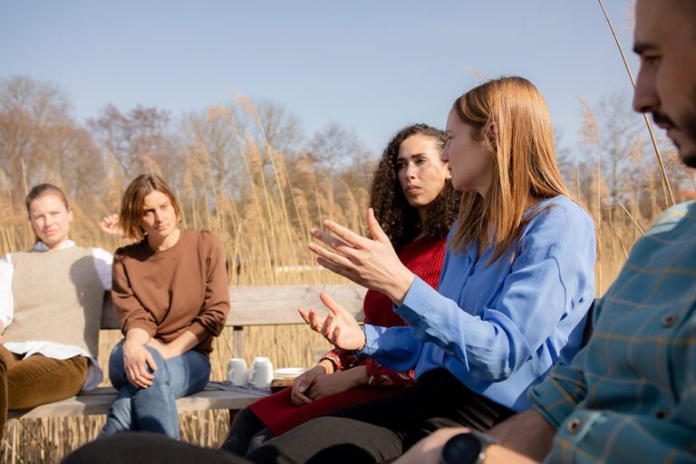 Eine Gruppe sitzt an einem See und betreibt Klimakommunikation.