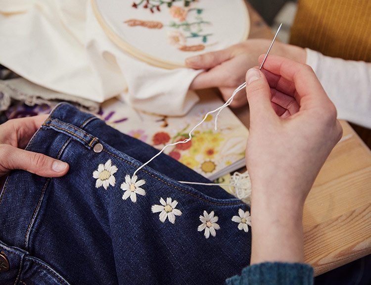 Am Rand der Tasche an der Jeans wurde eine Reihe Blumen gestickt.