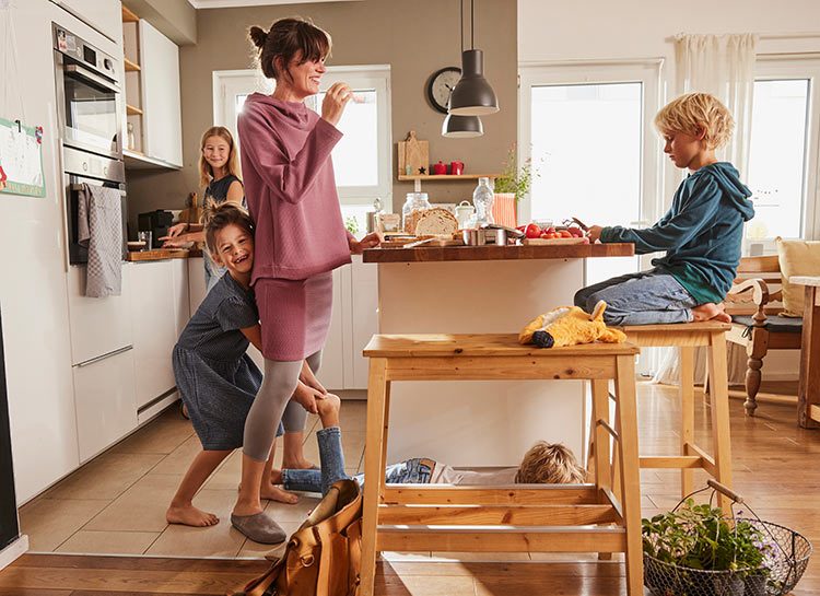 Eine Mutter steht mit ihren vier Kindern in der Küche und hat Spaß.