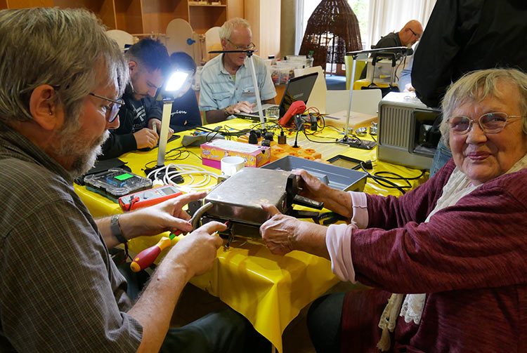 Verschiedene Menschen werkeln im Repair Café und haben Spaß.