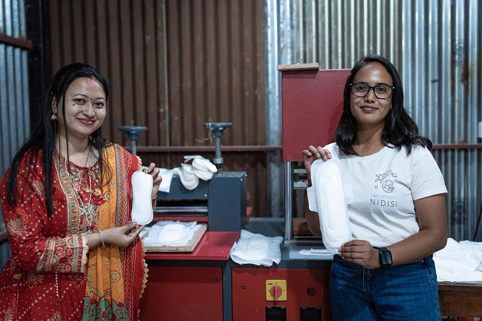 Zwei Frauen halten kompostierbare Binden aus dem Menstruationsprojekt in die Kamera.