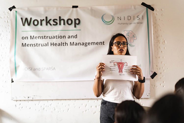 Een vrouw geeft een schoolklas voorlichting over menstruatie.