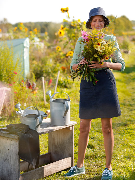 Frau trägt ein Bio-Rock und hält ein gepflückten Blumenstrauß in der Hand