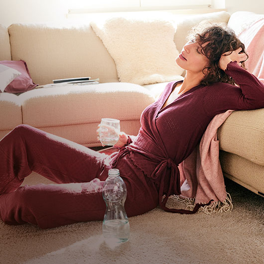 Frau im nachhaltigen Pyjama sitzt auf einem Teppich