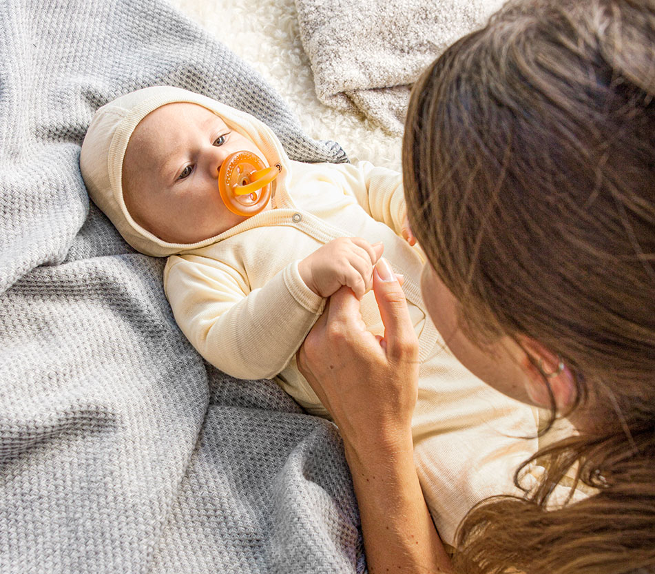 Baby in Erstausstattungs-Set mit seiner Mutter