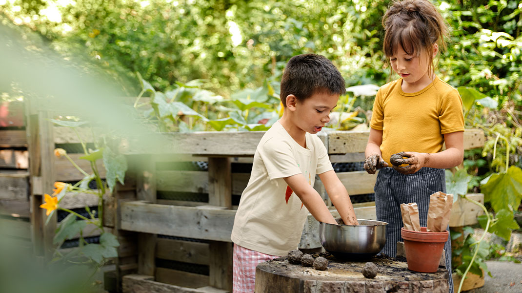 Kindern gärtnern zwischen Hochbeeten.