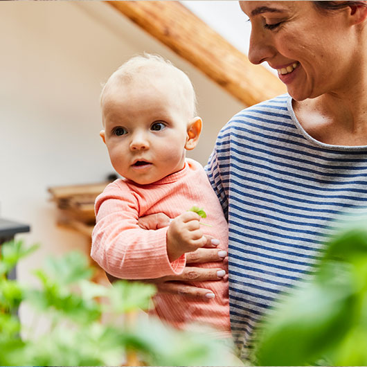 Baby in pfirsich-farbenem Ajour Body aus Bio-Baumwolle