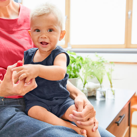 Baby in blauer Leinen-Shorts auf dem Schoß der Mutter