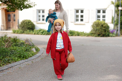 Mädchen in roter Walk-Jacke und Walk-Hose aus Bio-Schurwolle