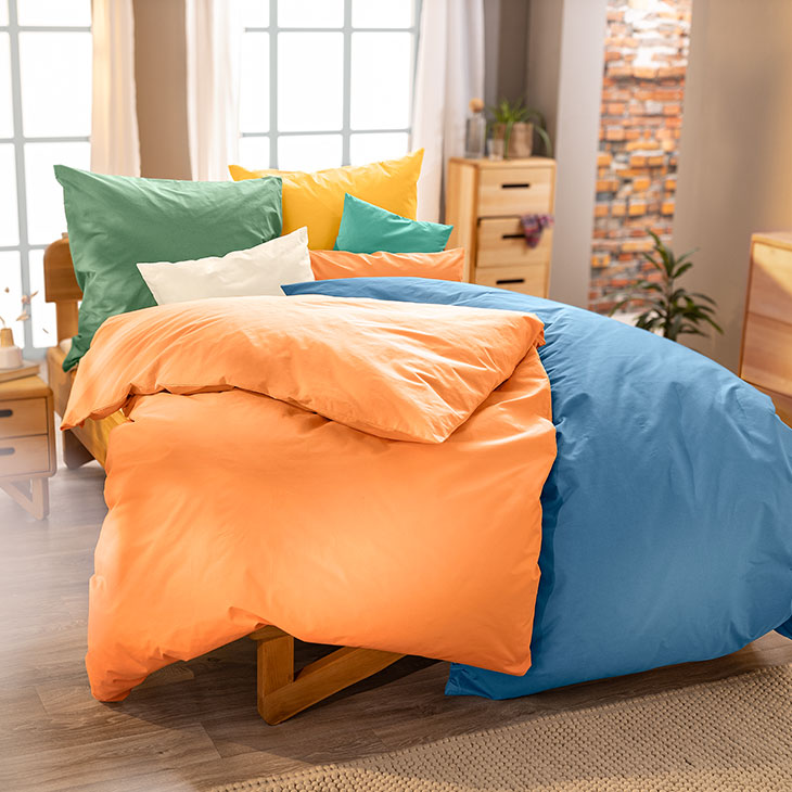 Gemütliches Bett mit farbenfroher Bettwäsche aus Bio-Baumwolle