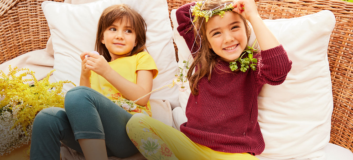 Kinder in Bio-Mode von Waschbär spielen mit Blumen auf einem Korbsofa